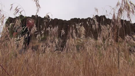 Ginger-male-hiker-walks-past-low-angle-shot-of-basalt-rock-columns