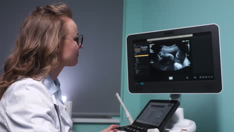 gynecologist observing a fetus on the ultrasound monitor while talking to her patient