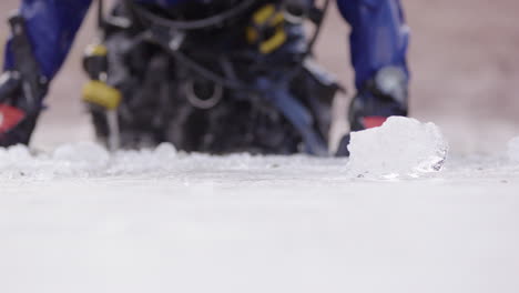 ice diver in dry suit and technical scuba dive gear exits water, shallow focus