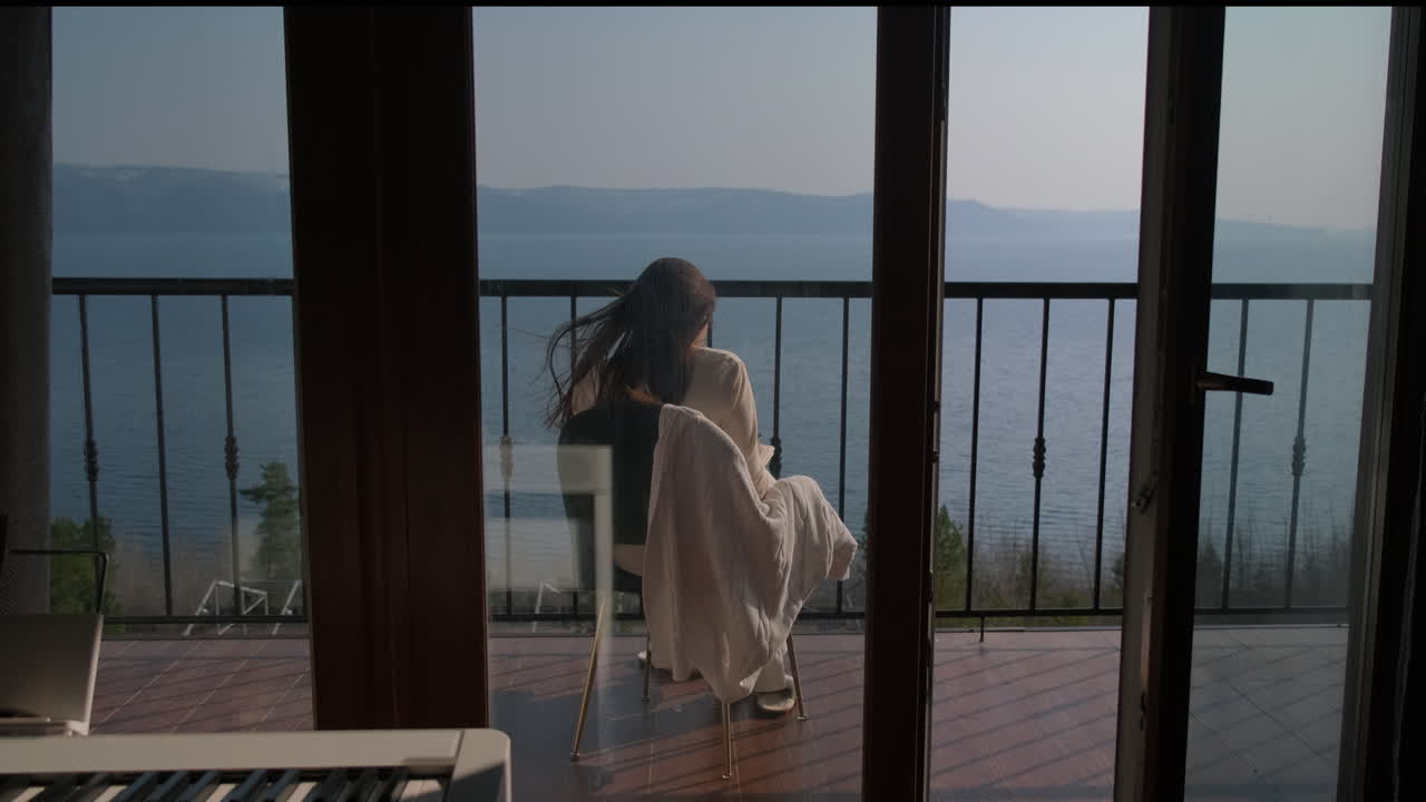 женщина отдыхает на балконе с видом на озеро