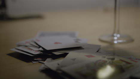 Handheld-close-up-shot-tracking-backwards-over-a-messy-deck-of-playing-cards-on-a-table