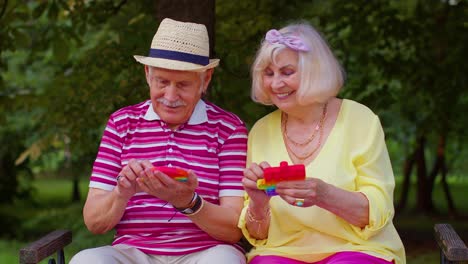 Sonriente-Mayor-Abuela-Abuelo-Jugando-Antiestrés-Pantalla-Táctil-Empujar-Pop-It-Popular-Juguete