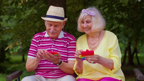 sonriente anciano abuela abuelo jugando a la pantalla táctil anti-estrés empujar pop es un juguete popular