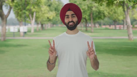 hombre indio sikh feliz mostrando el signo de la victoria en el parque