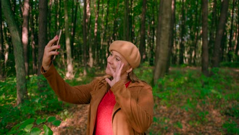 a happy woman taking selfie photos with a cellphone view of a green forest in the background