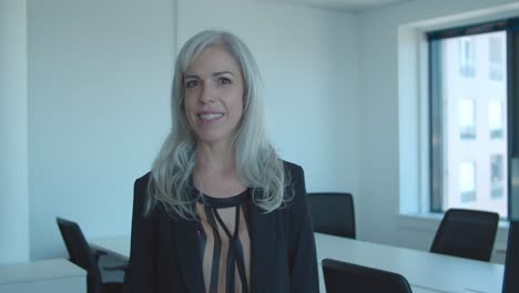 Happy-positive-middle-aged-businesswoman-standing-in-office