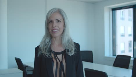 happy positive middle aged businesswoman standing in office