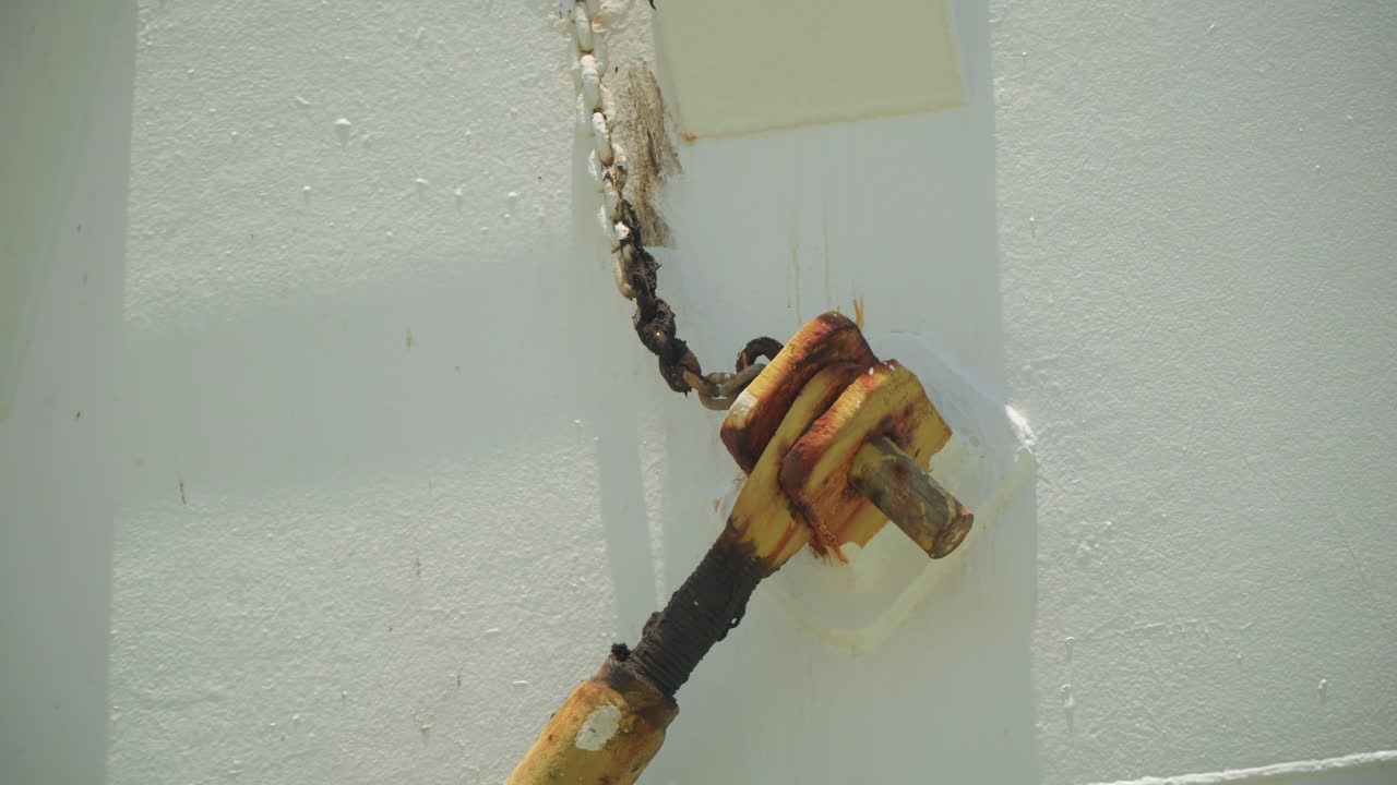 Corroded cable lug on white deck surface showing rust flakes, braided wire termination, yellow metal terminal with insulation tape, soft natural light, inspection mood, textures of oxidation and aging