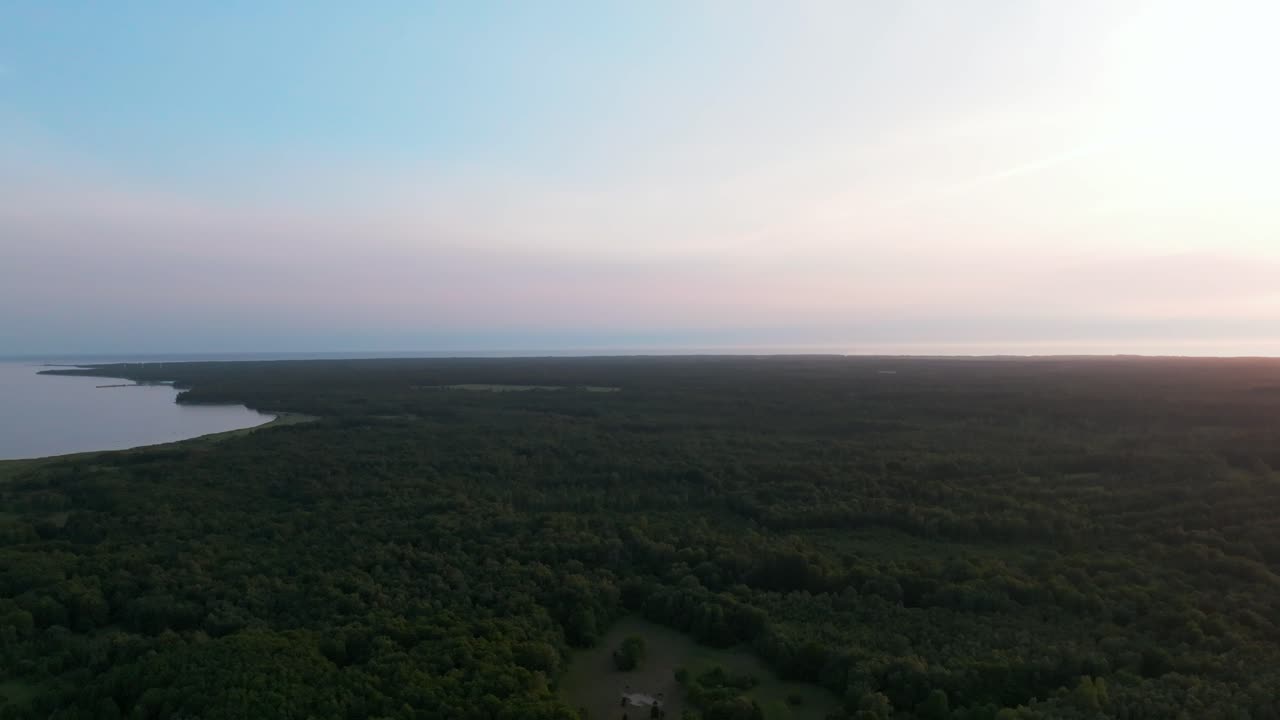 Flying over a forested coastal landscape at evening light