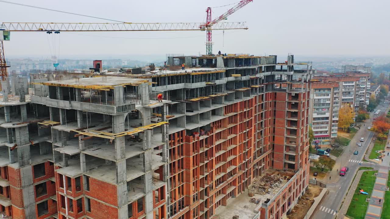 Construction site of modern skyscraper. Aerial side view on a new high-rise building in a new residential complex of a megacity.