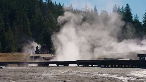 yellowstone national park geothermal area with steam and tourists