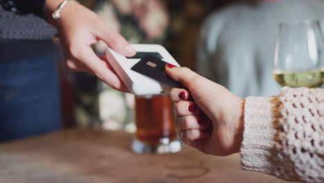 close up of customer paying in hotel restaurant using contactless card reader