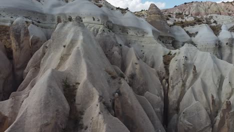 Drone-panning-sideways-from-the-right-to-the-left-side-of-the-frame,-showing-the-natural-rock-formations-of-Cappadocia-located-in-Turkey