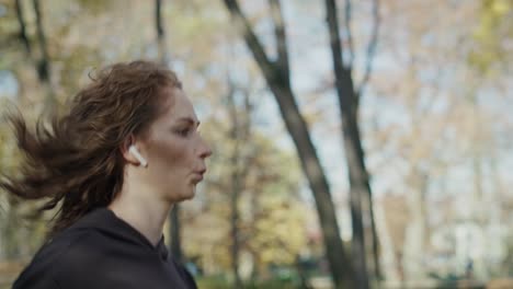 mujer roja caucásica corriendo en el parque en otoño