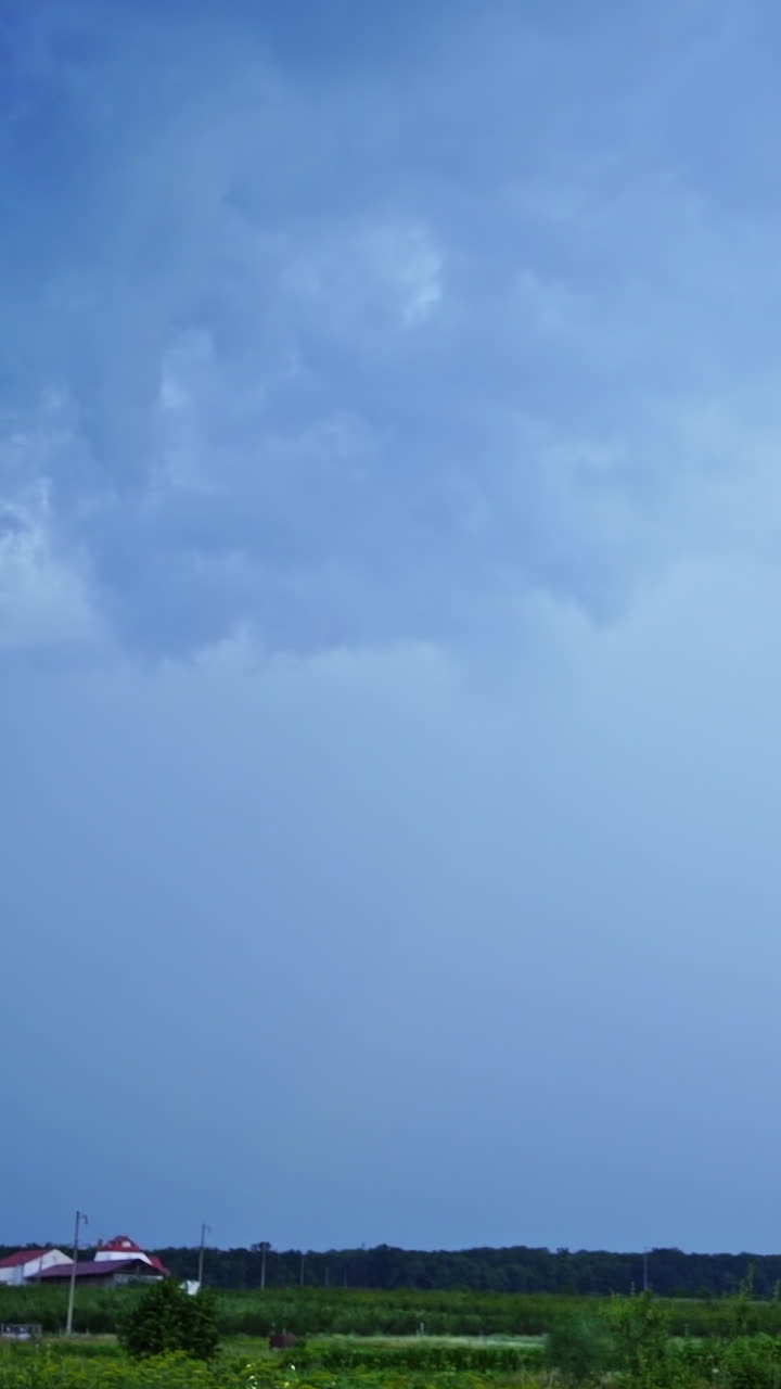 Real flashes of lightning on the blue sky background. The blue sky changes its color into orange after the bright lightning. Vertical video