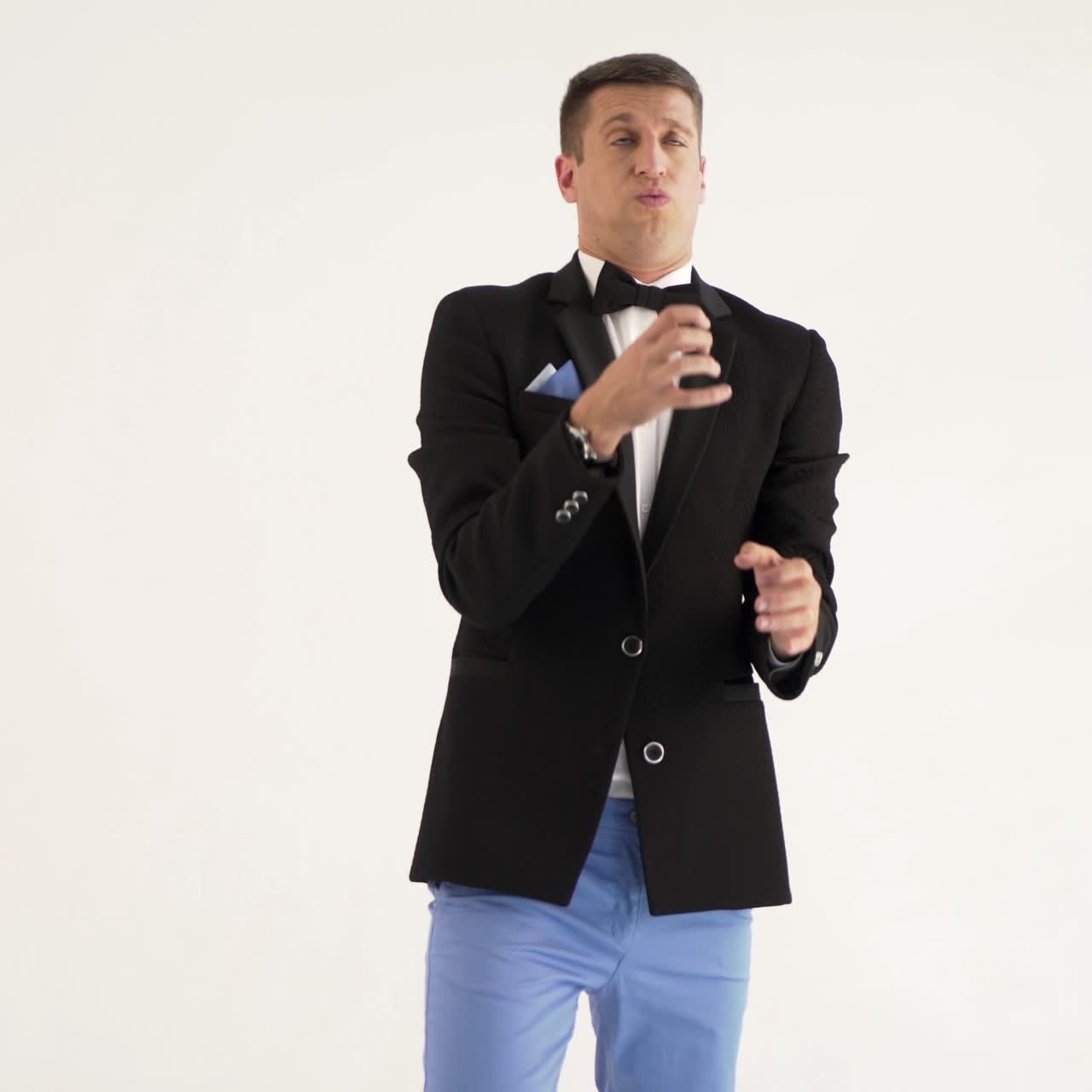 fun showman in black jacket is showing how a trumpet player plays a trumpet at concert on a white background in the studio