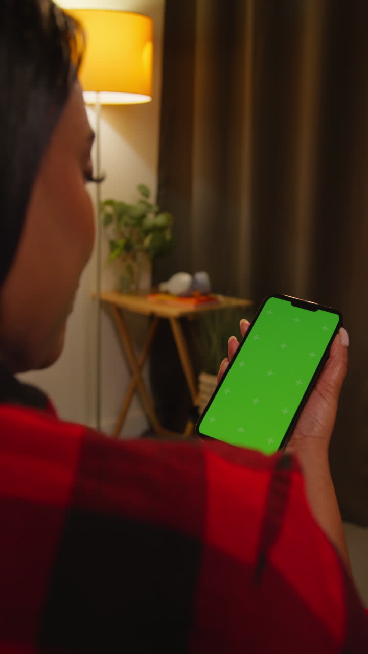 Woman looking at a green screen phone at night