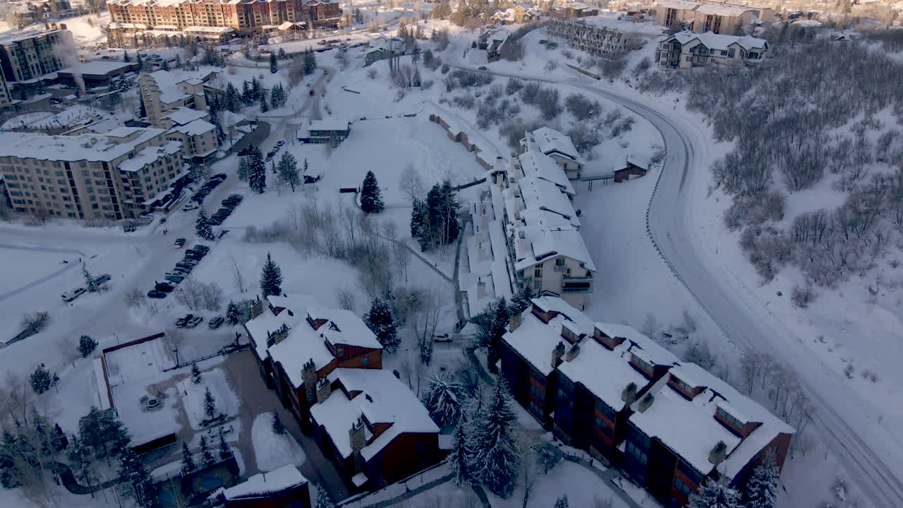 Aerial reveal of steamboat springs city, condos, mountain, and road in winter