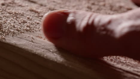 Human-Hand-On-Wooden-Plank-Removing-Sawdust