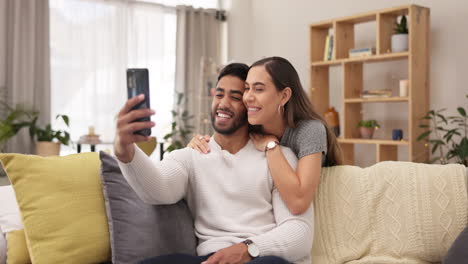 Happy-couple,-hug-and-kiss-in-selfie-on-sofa