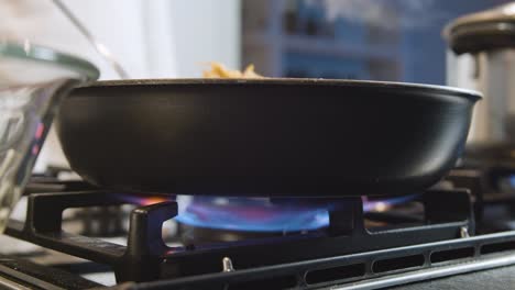 chef fries potatoes in pan. low angle and close up