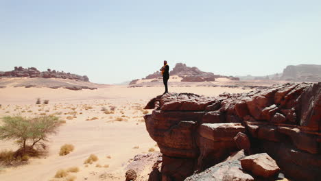 Mann-Steht-Am-Rande-Eines-Felsens-Und-Blickt-Auf-Die-Weite-Wüstenlandschaft-In-Djanet,-Algerien