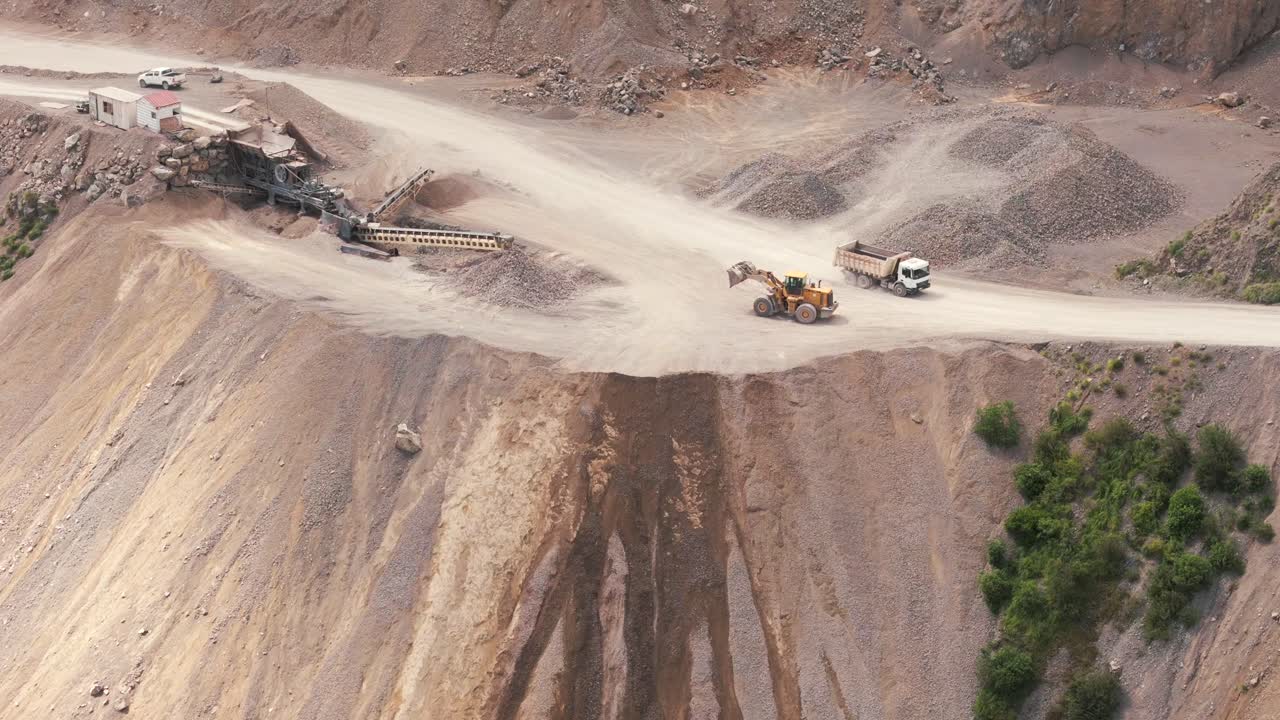 Aerial view of a bulldozer clearing the dirt road at a limestone mining site, transporting minerals at scale in the province of Jujuy, Argentina