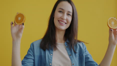 woman holding orange slices in front of face
