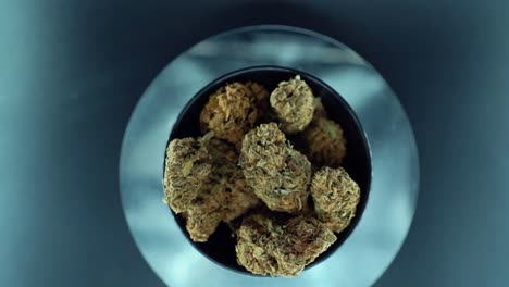 una grúa cinematográfica de arriba hacia abajo detallada suave zoom out movimiento tiro de una planta de cannabis, cepas híbridas de naranja, tipo indica, flor de marihuana, cámara lenta 120 fps, luces de estudio, soporte giratorio brillante
