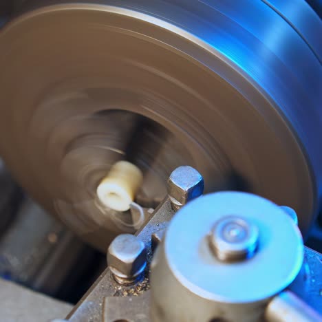 Little plastic detail being grinded out in the lathe. White flakes flying away from the lathe. Close up