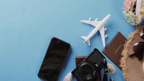 close up of white plane model, smartphone, camera, passport and copy space on blue background