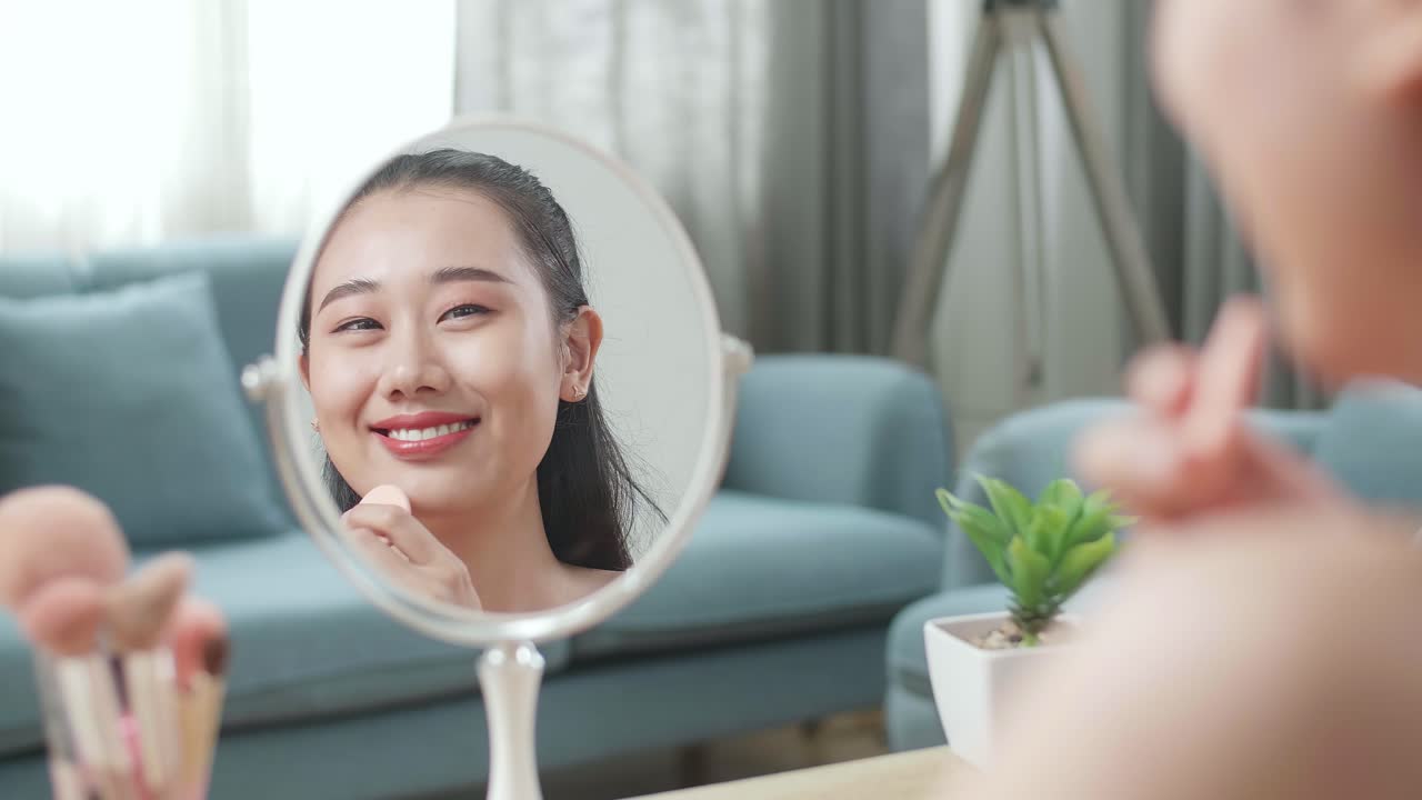 거울에 반사 걱정 젊은 아시아 여성은 가정에서 메이크업하는 동안 웰니스 피부 관리를 위해 파우더 얼굴을 적용