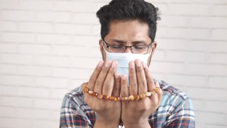 muslim man in face mask keep hand in praying gestures during ramadan,