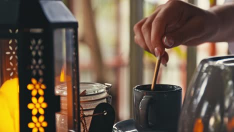 woman with french manicure swirling honey in tea with a spoon