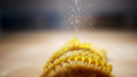 slow motion view of an unique perspective of semolina particles and flour falling over yellow homemade pasta