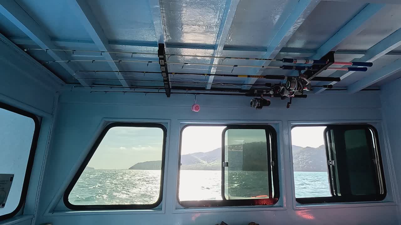 A serene view from inside a fishing boat, showcasing the ocean and sky through windows, with gentle camera movement