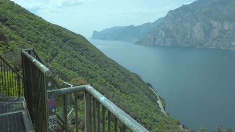 Lake-Garda-railing-at-Busatte-during-a-storm,-metal-pathway,-with-dramatic-sky,-water,-mountain,-clouds