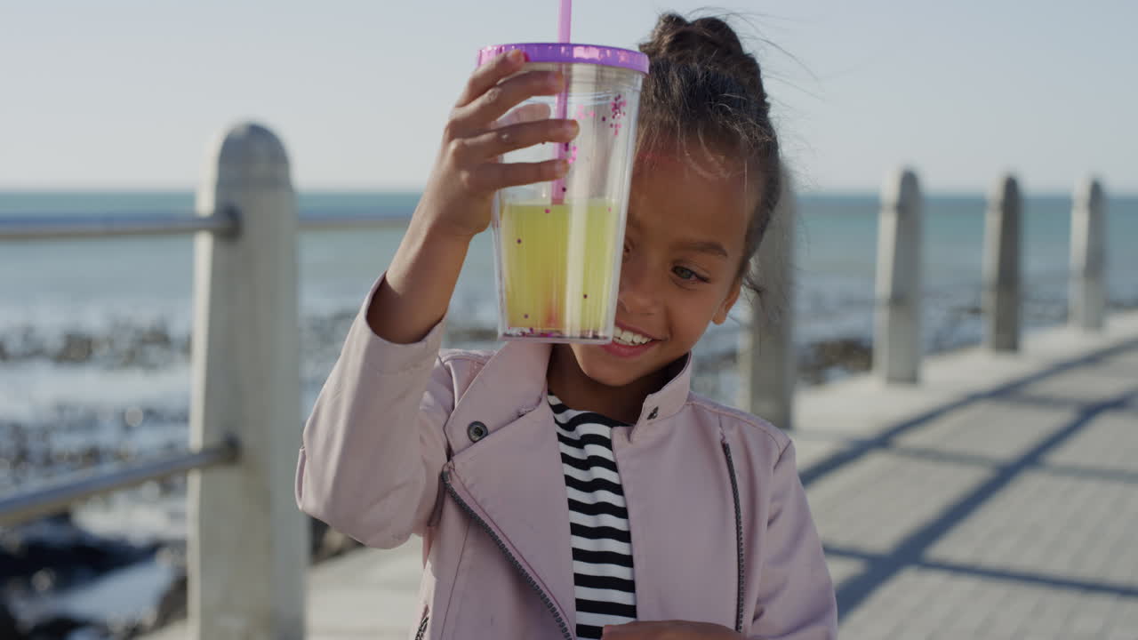 portrait beautiful little girl holding juice smiling happy enjoying warm summer vacation on beach seaside