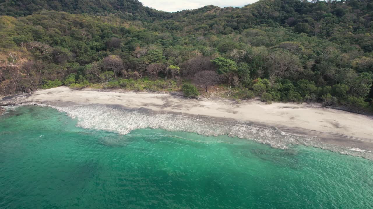Drone semi orbit capturing the remote Huevos Beach and surrounding forest in Papagayo Peninsula