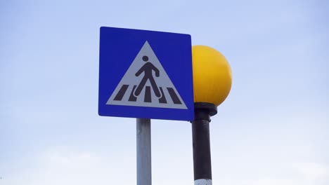 ongereguleerde voetgangersovergangsbord tegen blauwe zonsondergangshemel. geel rond verkeerslicht knipperend