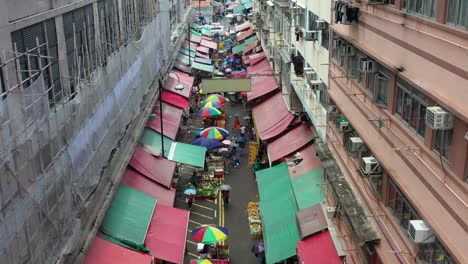 overview of busy street lined with food stalls in hong kong under the rain