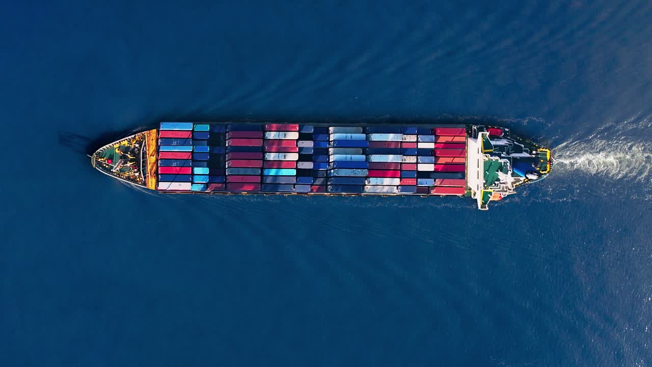 Container ship navigating calm waters with brightly colored shipping containers amidst global trade challenges