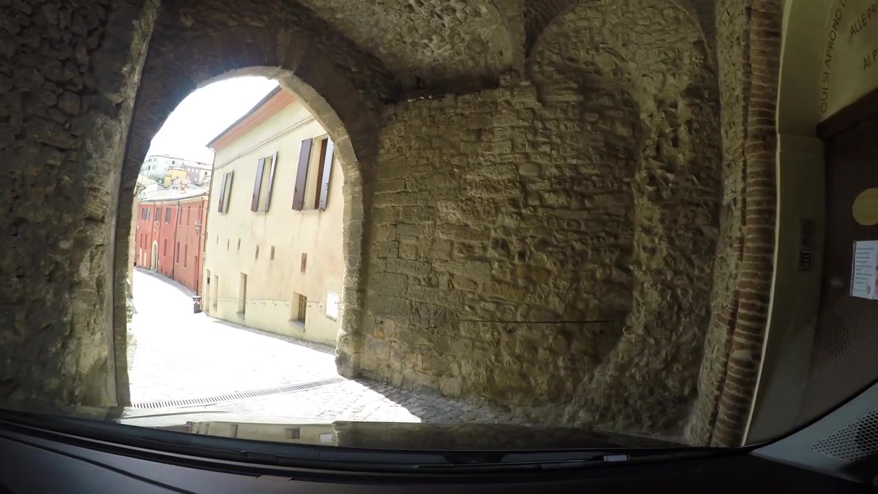 Guidando attraverso un vecchio tunnel iconico nelle strette vie del comune di Verucchio in Italia, POV.