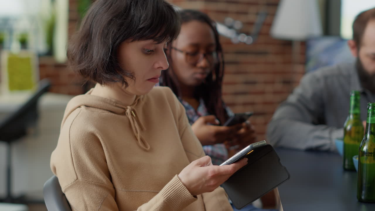 Female person browsing internet on mobile phone at fun gathering