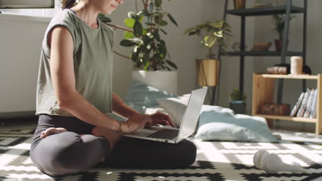 woman sitting in lotus pose and typing on laptop