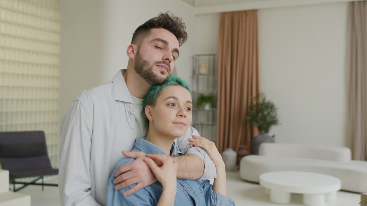 hombre guapo abrazando tiernamente a su novia desde atrás en casa