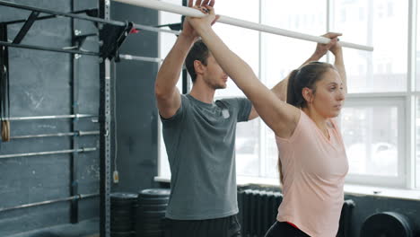 personal trainer assisting woman with upper body exercise