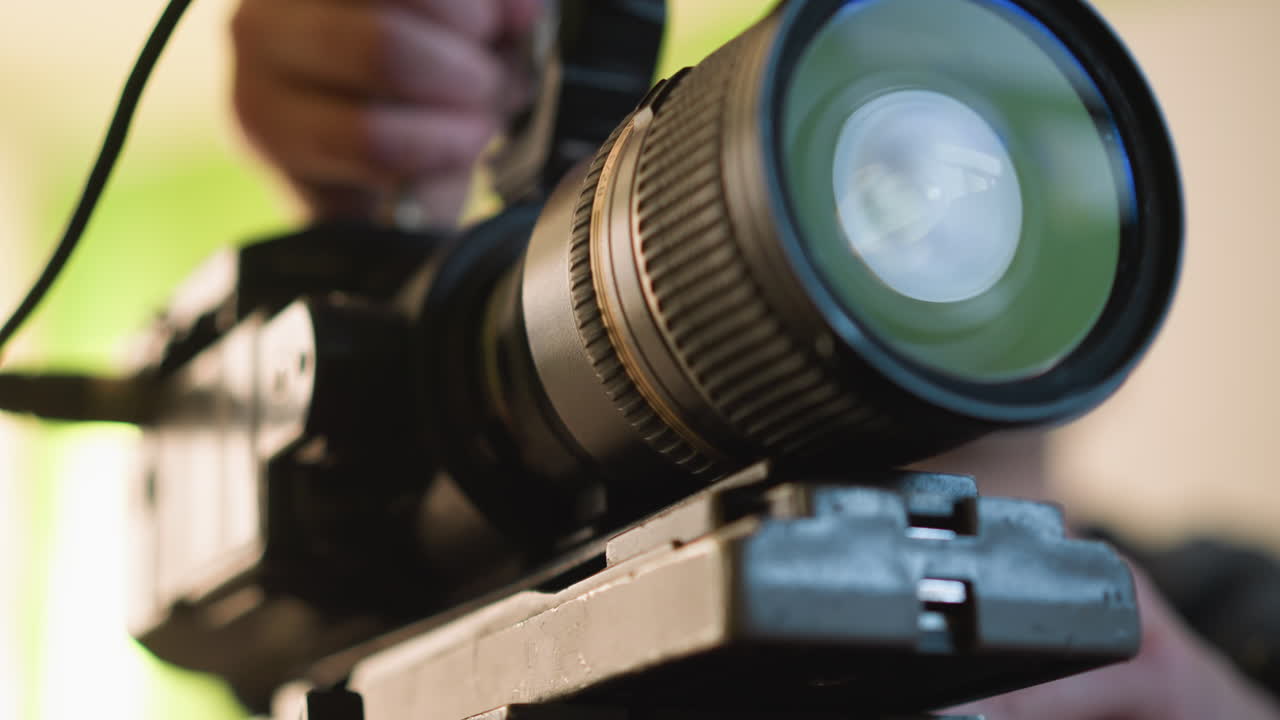 Close-up of hand placing camera onto tripod quick release plate. Lens caps on table