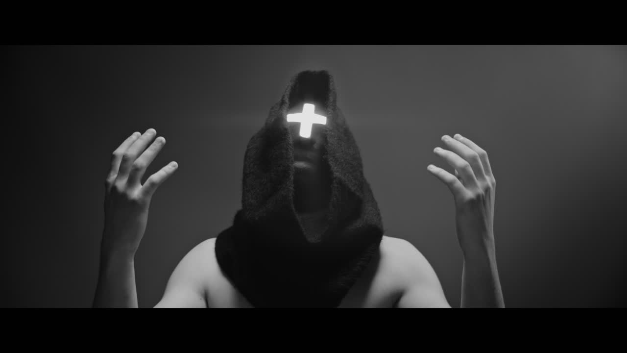 Masked man with cross of light glowing on his face prays