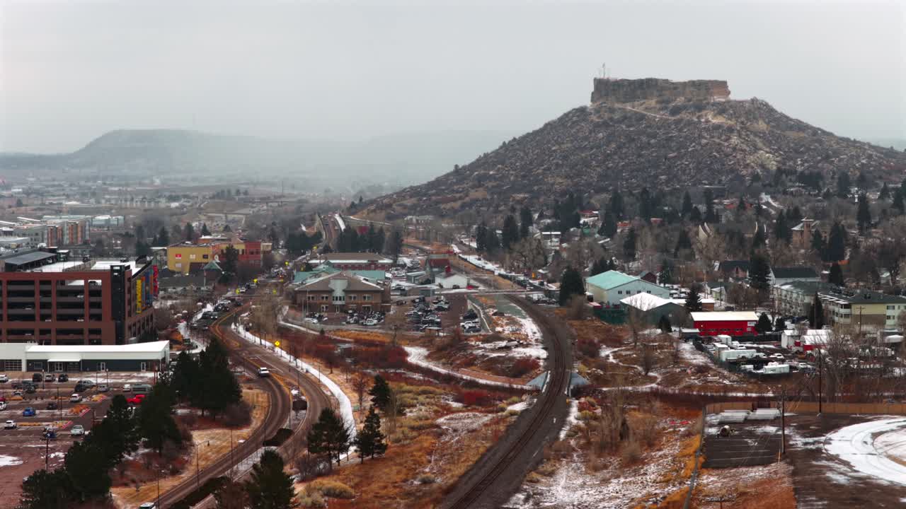 Città di Castle Rock, Colorado, drone aereo, Catena Front Range, città a sud di Denver, mesa coperta di neve, mattinata invernale nevosa, giornata nuvolosa con neve, auto, binario ferroviario, edificio, quartiere, centro città, inquadratura statica.